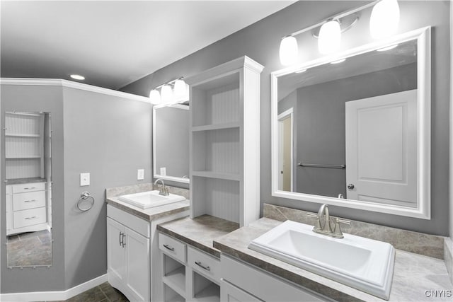 full bath featuring recessed lighting, baseboards, two vanities, and a sink