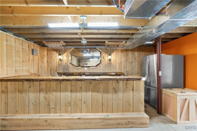 unfinished below grade area with freestanding refrigerator and wooden walls