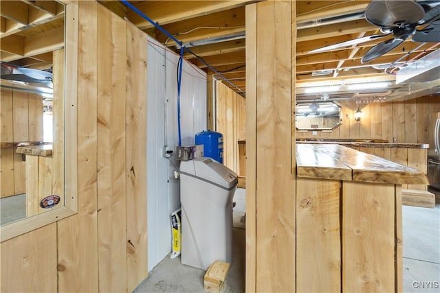 below grade area with wooden walls and freestanding refrigerator