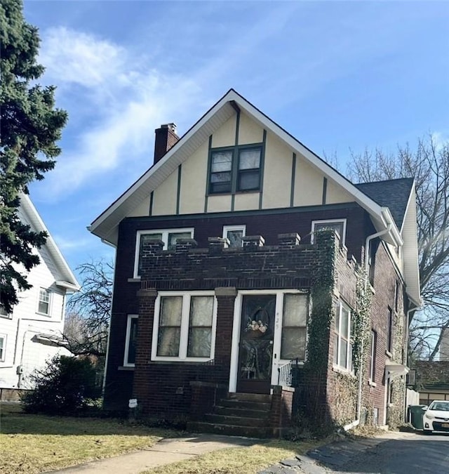 view of front facade featuring a chimney, stucco siding, and brick siding