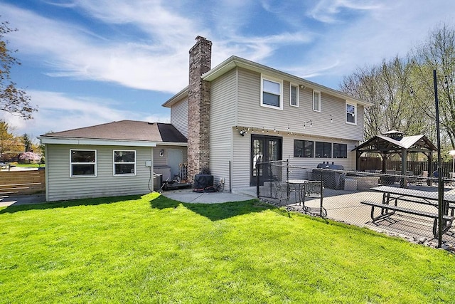 rear view of property featuring a lawn, fence, a chimney, a patio area, and a gazebo