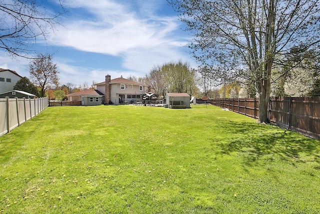 view of yard featuring an outdoor structure, a fenced backyard, and a storage unit