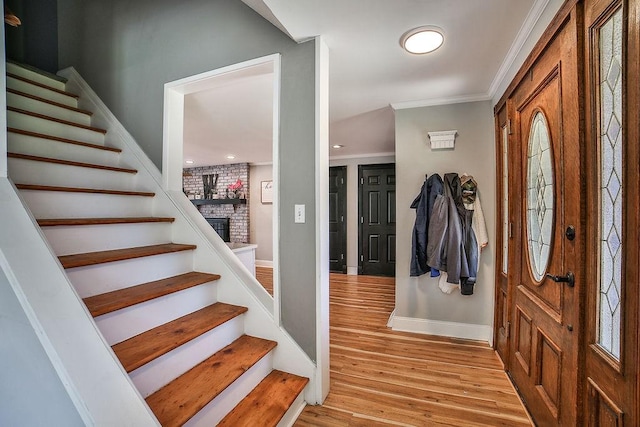 entryway with visible vents, ornamental molding, stairs, baseboards, and light wood finished floors