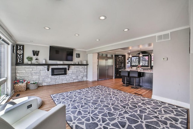 living area featuring crown molding, recessed lighting, visible vents, and wood finished floors