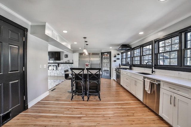 kitchen featuring crown molding, recessed lighting, high end appliances, and a sink
