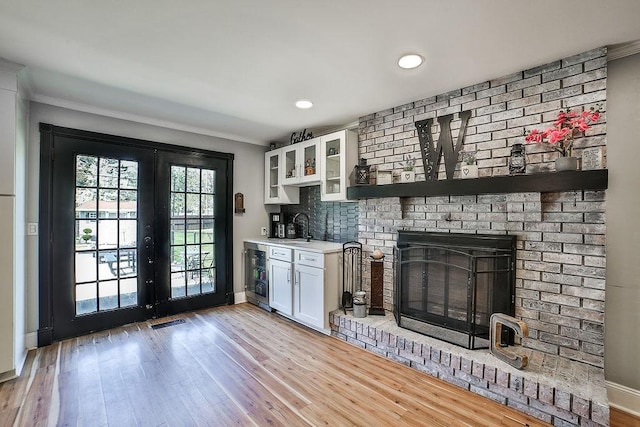interior space featuring a sink, baseboards, light wood finished floors, beverage cooler, and ornamental molding
