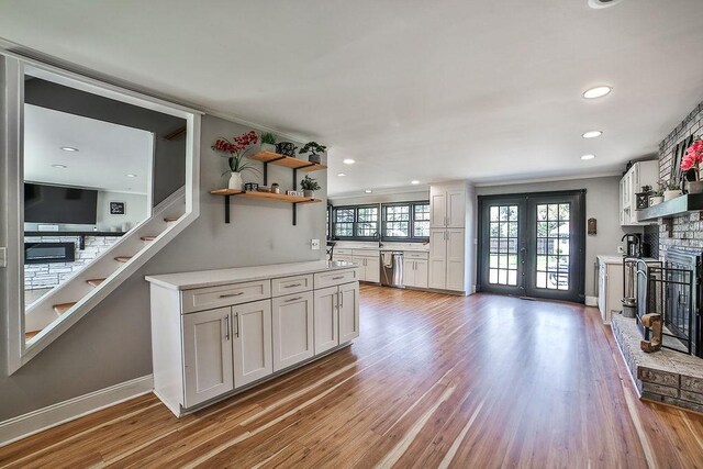 kitchen with open shelves, light wood-style flooring, dishwasher, and a fireplace