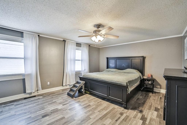 bedroom with crown molding, a ceiling fan, a textured ceiling, and wood finished floors