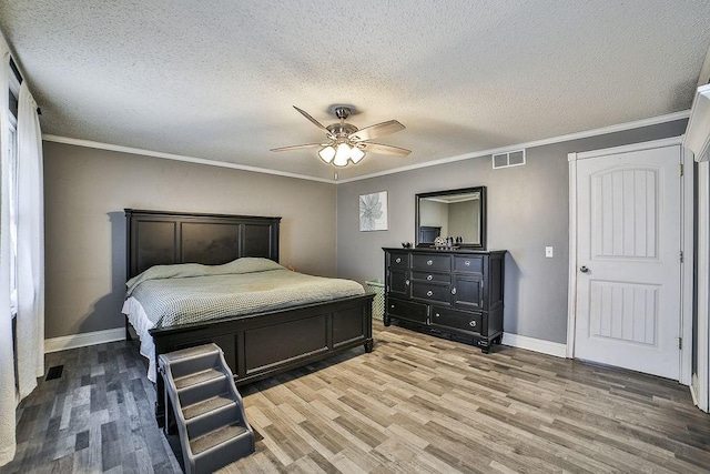 bedroom featuring a ceiling fan, a textured ceiling, visible vents, wood finished floors, and baseboards