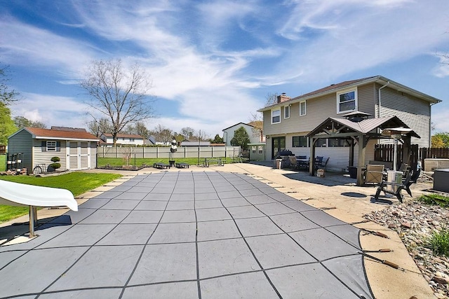 view of pool featuring a gazebo, an outbuilding, a fenced backyard, and a patio area