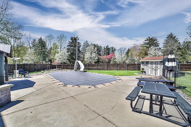 view of swimming pool featuring an outdoor structure, a fenced backyard, a shed, a patio area, and a yard