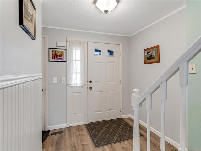entrance foyer featuring visible vents, ornamental molding, and wood finished floors