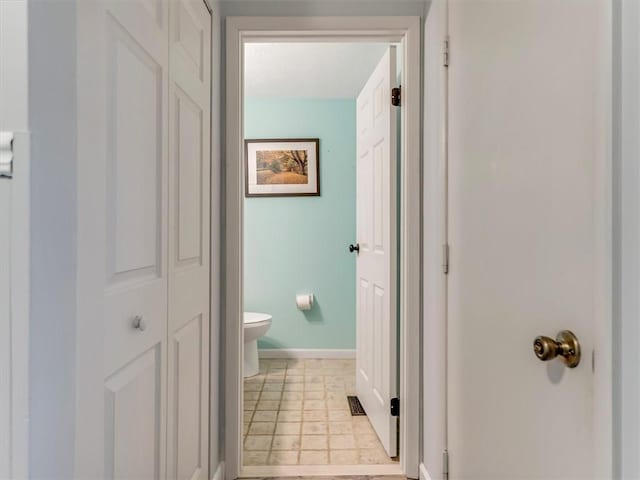 bathroom with toilet, baseboards, and a closet