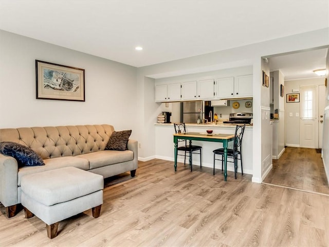 living room featuring baseboards, recessed lighting, and light wood-style flooring