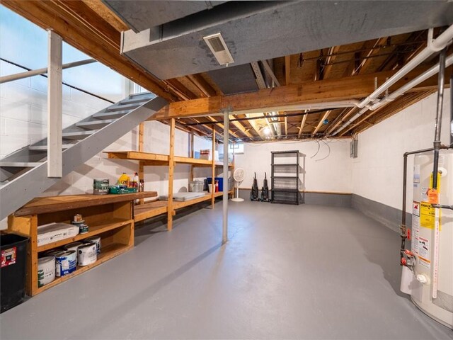 unfinished below grade area featuring stairs, baseboards, visible vents, and water heater
