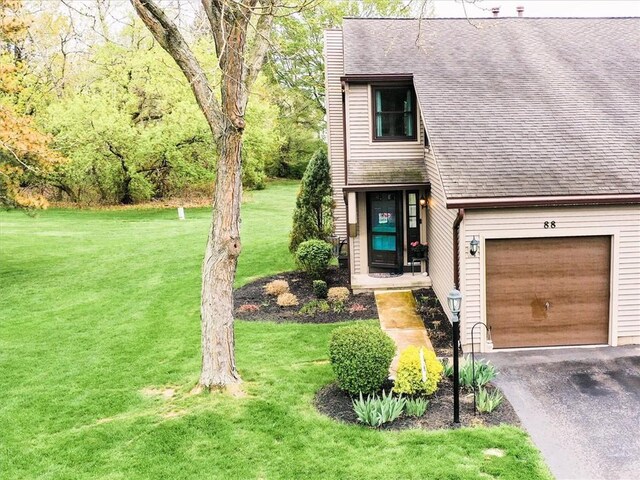 view of front facade featuring a garage, a front lawn, roof with shingles, a chimney, and driveway