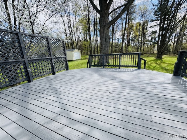 deck with a storage shed, a lawn, and an outbuilding