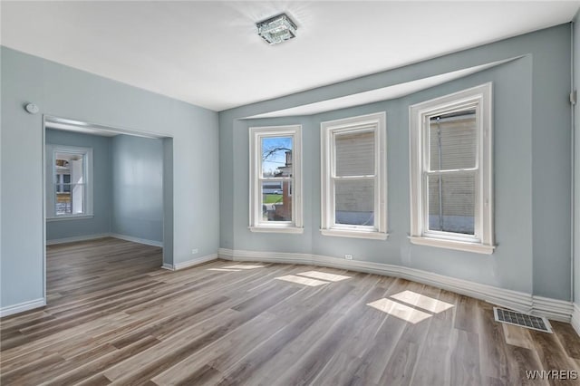 empty room with visible vents, baseboards, and wood finished floors
