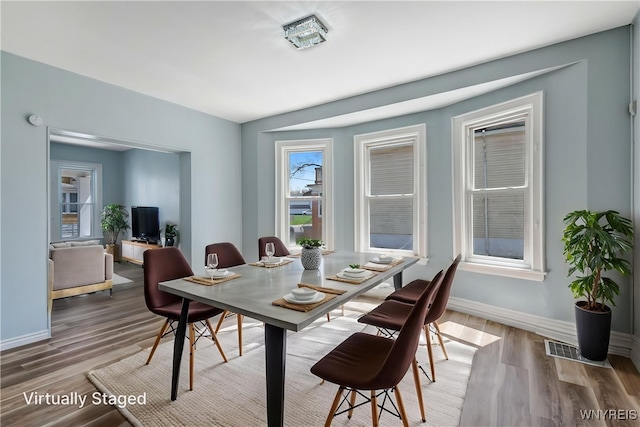 dining area with baseboards, wood finished floors, and visible vents
