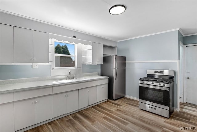 kitchen with a sink, light countertops, ornamental molding, stainless steel appliances, and light wood-style flooring