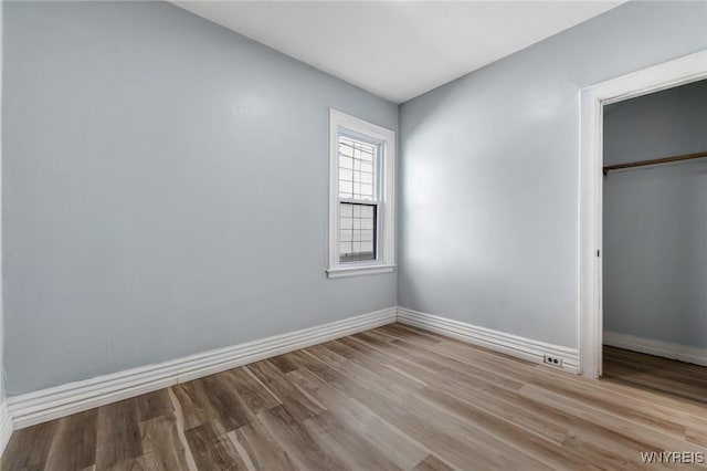 unfurnished bedroom with baseboards, wood finished floors, and a closet