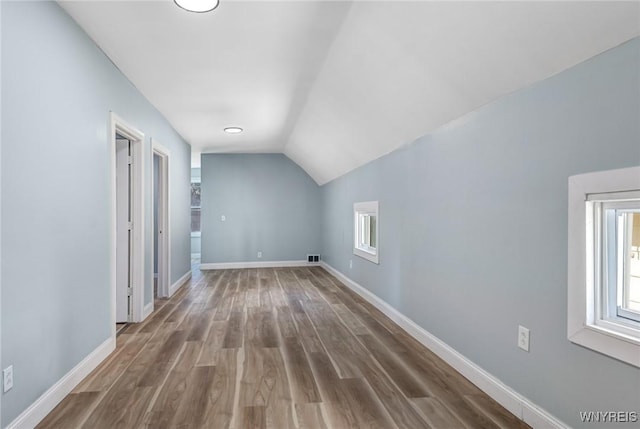 additional living space featuring baseboards, visible vents, wood finished floors, and lofted ceiling