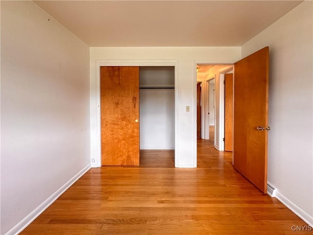 unfurnished bedroom featuring baseboards, a closet, and light wood-type flooring