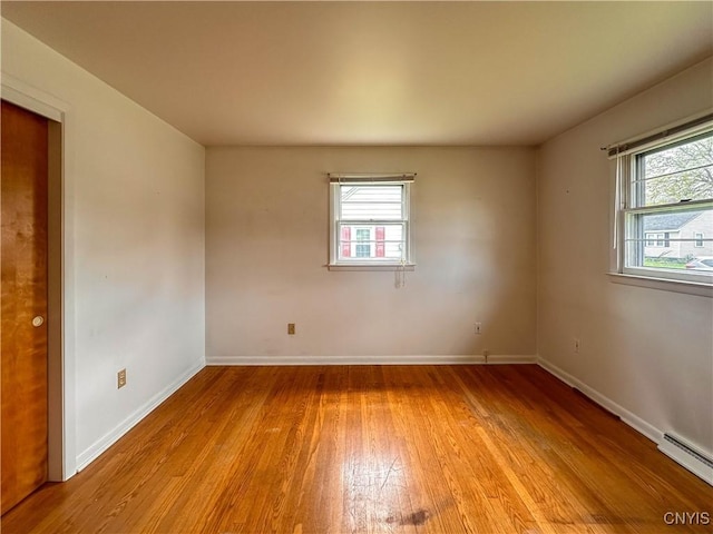unfurnished room featuring baseboards, light wood finished floors, and a baseboard heating unit