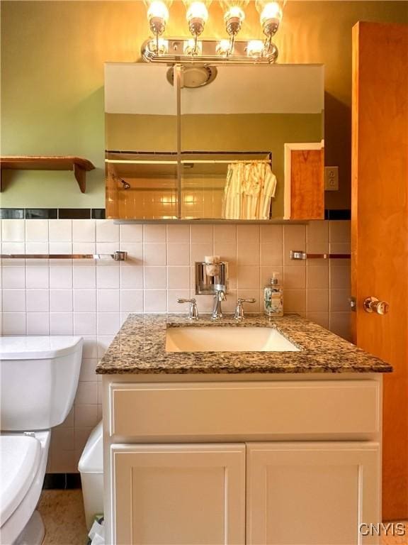 bathroom featuring vanity, toilet, and tile walls