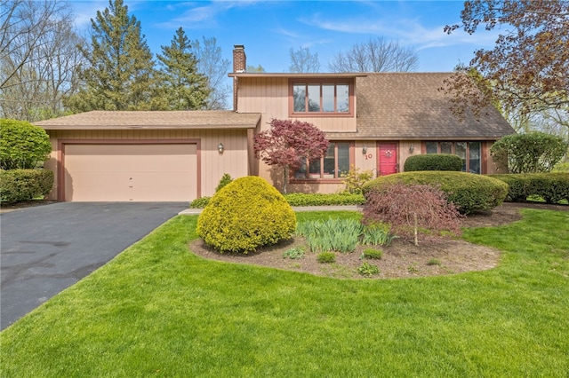 view of front of property featuring a garage, a chimney, a front yard, and aphalt driveway