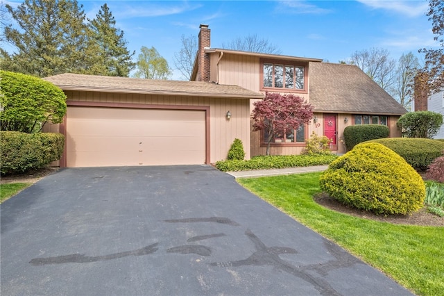 view of front facade featuring an attached garage, a chimney, and aphalt driveway