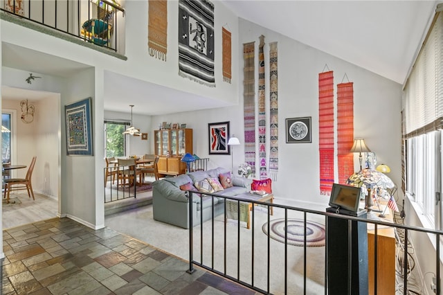 living area featuring high vaulted ceiling, baseboards, and stone tile flooring