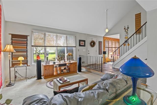 carpeted living area with high vaulted ceiling, a healthy amount of sunlight, and stairway