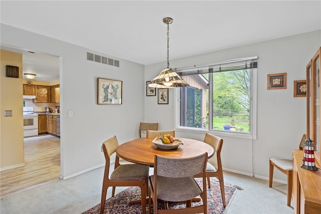 dining room featuring visible vents, baseboards, and light colored carpet