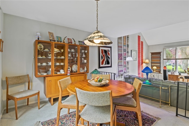 dining room featuring baseboards, light carpet, and vaulted ceiling