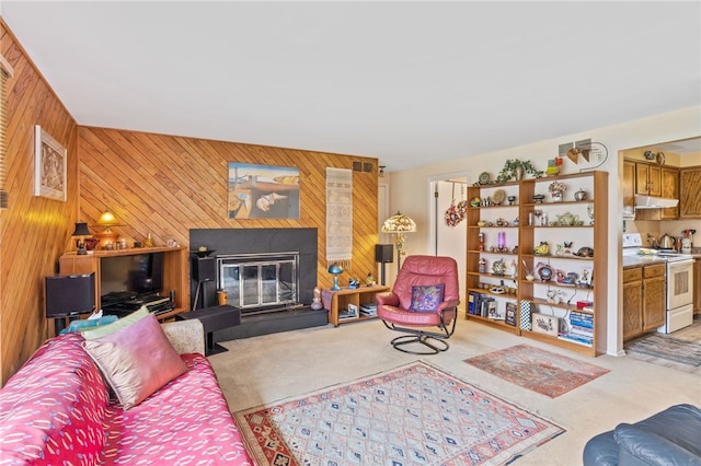 living area with wood walls, a glass covered fireplace, and light carpet