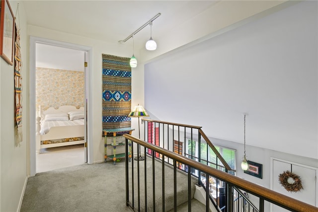hall featuring baseboards, carpet flooring, and an upstairs landing