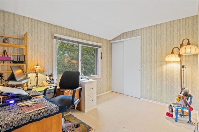 carpeted home office with wallpapered walls, vaulted ceiling, and baseboards