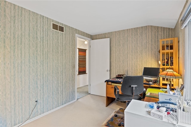 carpeted home office with vaulted ceiling, wallpapered walls, and visible vents
