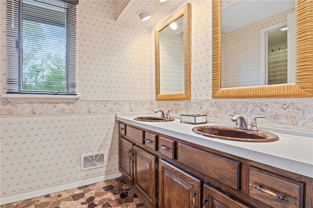 bathroom with double vanity, wallpapered walls, visible vents, and a sink