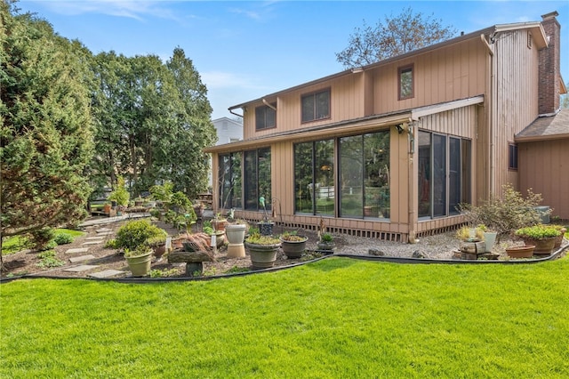 back of house with a lawn, a chimney, and a sunroom