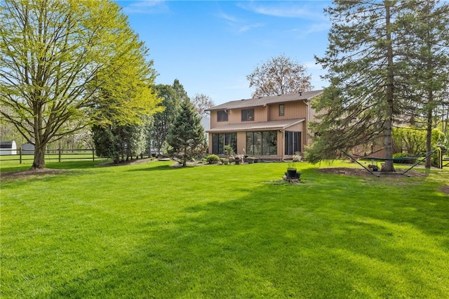rear view of house featuring fence, a sunroom, and a lawn