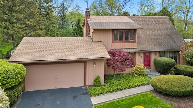 view of front of property featuring a garage, roof with shingles, aphalt driveway, and a chimney