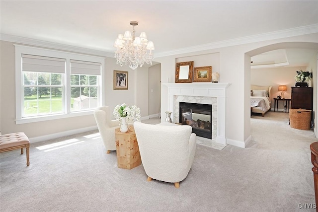 living area featuring light colored carpet, a high end fireplace, arched walkways, baseboards, and ornamental molding