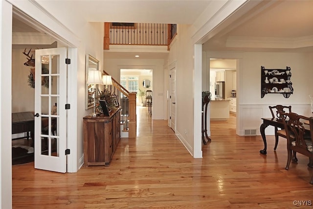 corridor with crown molding, visible vents, stairs, and light wood-style floors