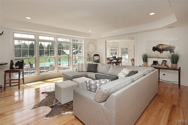 living room featuring crown molding, a raised ceiling, recessed lighting, and light wood-style flooring