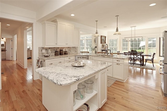 kitchen with a peninsula, open shelves, white cabinetry, and a sink
