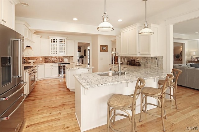 kitchen featuring a peninsula, premium appliances, decorative backsplash, and a sink