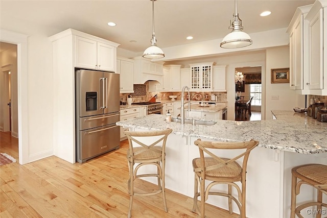 kitchen with decorative backsplash, a peninsula, a breakfast bar, high quality appliances, and a sink