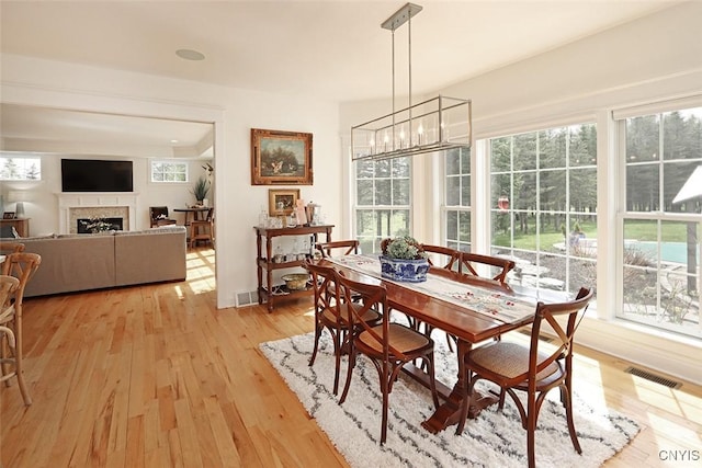 dining space with visible vents, light wood-style flooring, and a fireplace